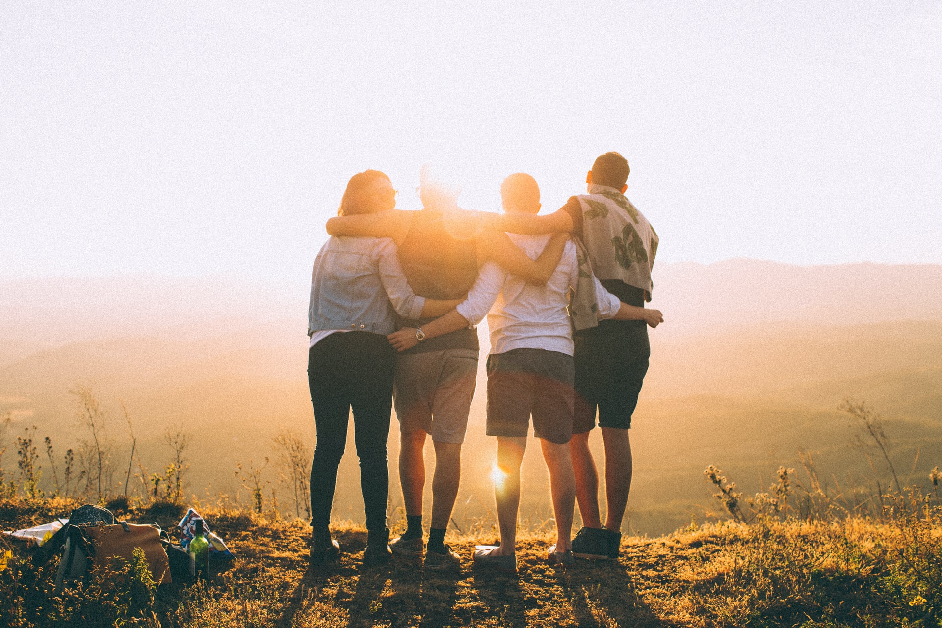 4 students stand with their arms around each other looking at the sunset